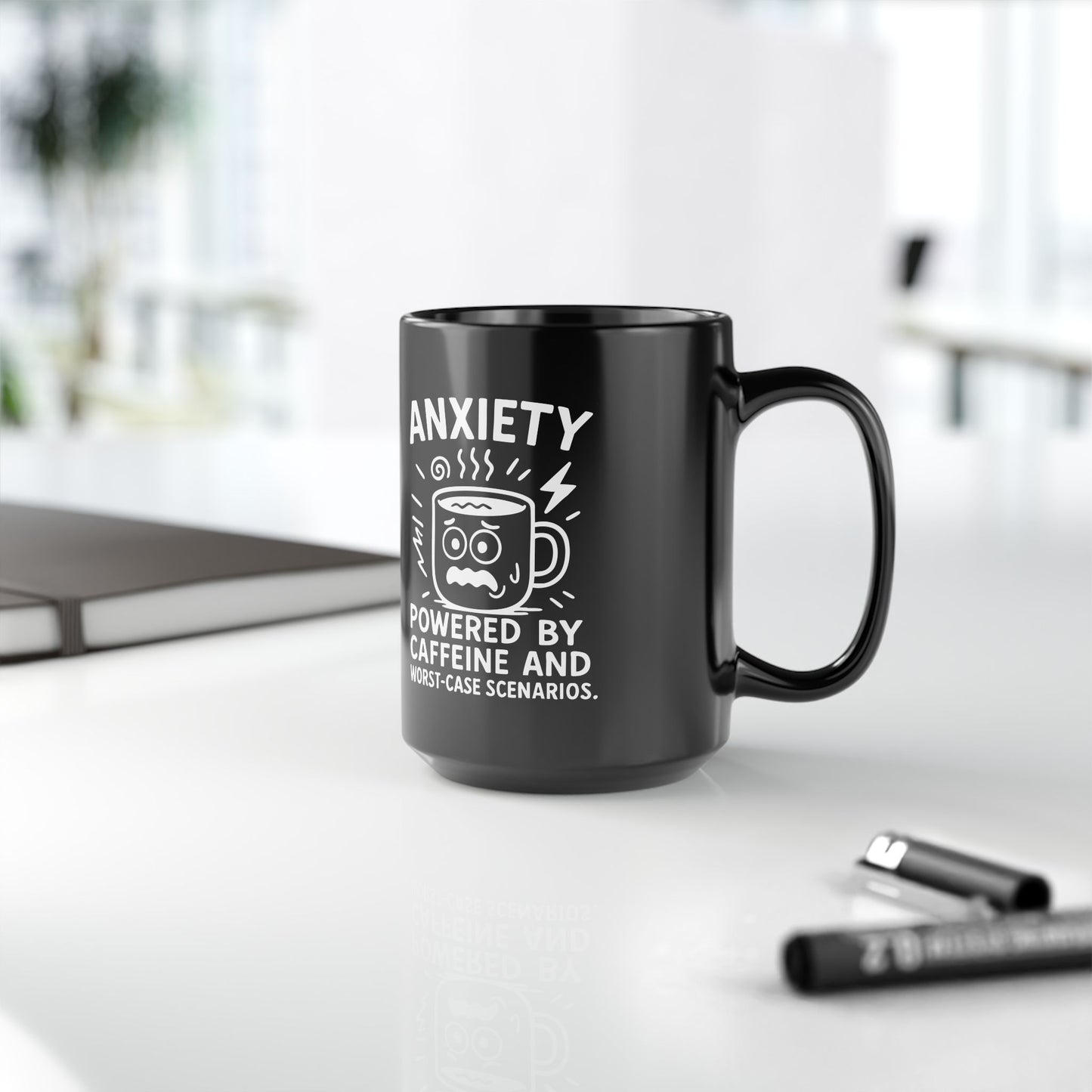 Black ceramic mug with white text reading "Anxiety powered by caffeine and worst-case scenarios" and a distressed cartoon coffee cup illustration.