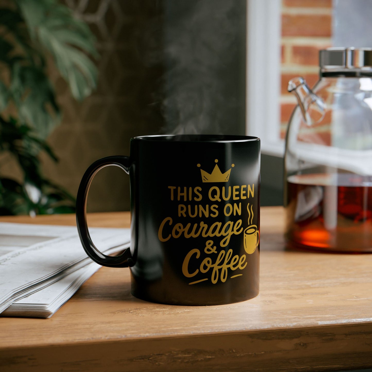 Black ceramic coffee mug with the motivational quote "This Queen Runs on Courage & Coffee" in gold lettering with a crown and steaming coffee cup graphic.