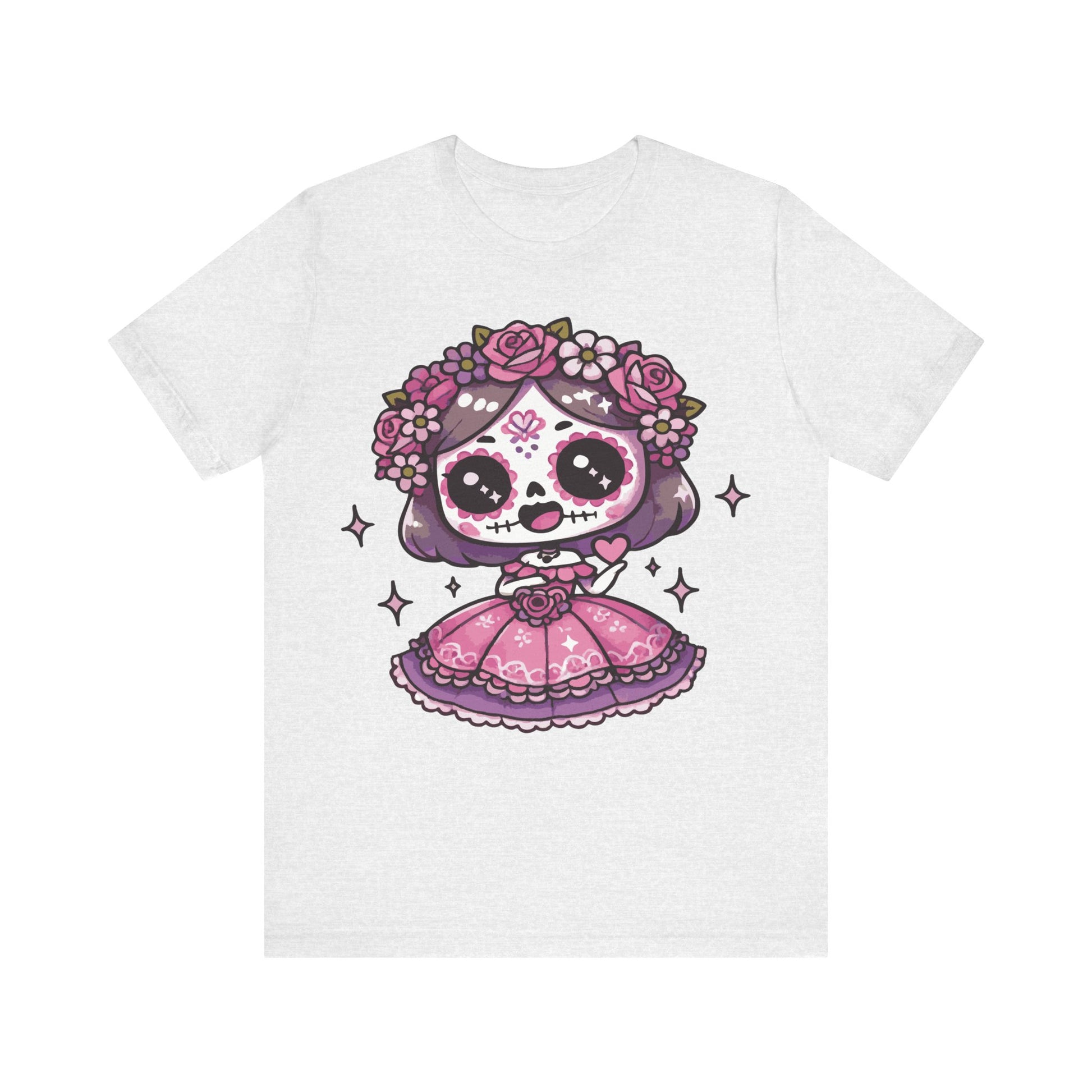 Ash color t-shirt featuring a kawaii chibi sugar skull girl with purple hair, pink sugar skull face paint, floral crown of roses, and a pink Mexican folk dress with sparkles.

